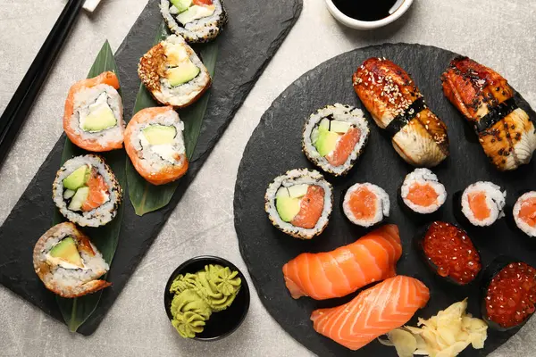 Flat lay composition with delicious sushi rolls on light grey table