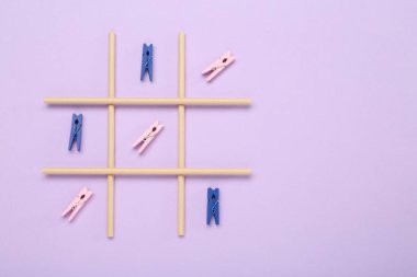 Leylak arkaplanındaki mandallarla yapılan tik tak parmak oyunu, üst görünüm