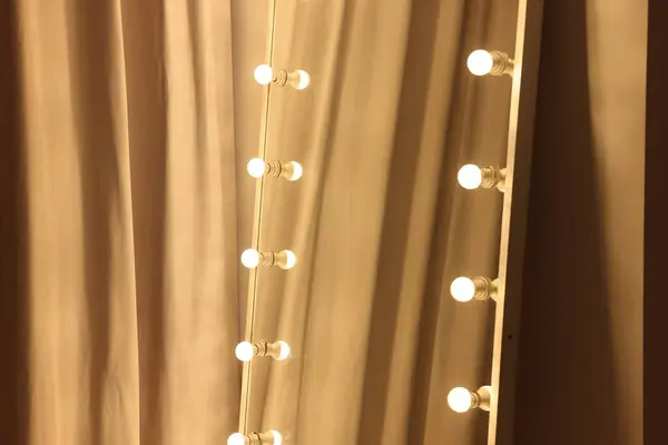 Modern mirror with light bulbs in makeup room, closeup