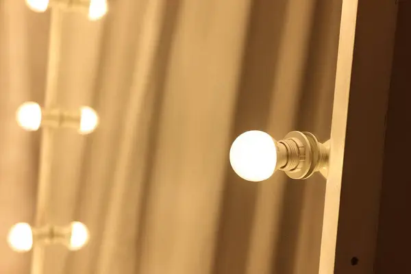 Modern mirror with light bulbs in makeup room, closeup