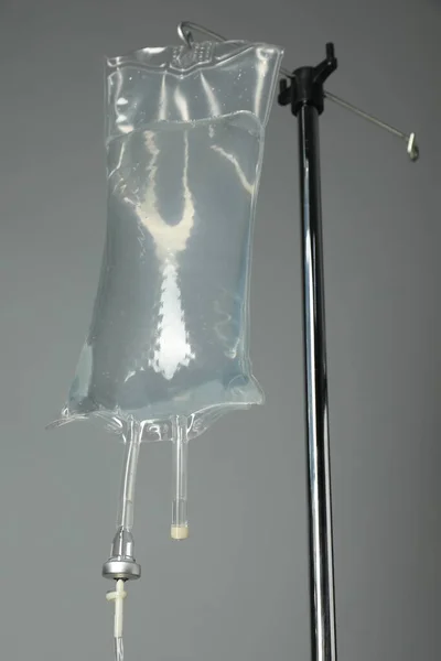 IV infusion set on pole against grey background, closeup