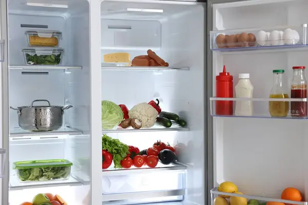 Open refrigerator full of different products indoors