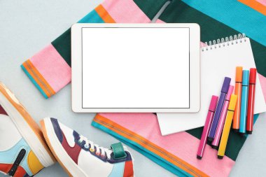Modern tablet, giysi ve arkaplanda kırtasiye malzemesi, düz bir zemin. Metin için boşluk