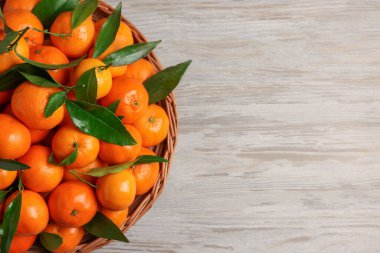 Taze, sulu mandalinalar ve beyaz ahşap masa üzerinde yeşil yapraklar. Metin için boşluk
