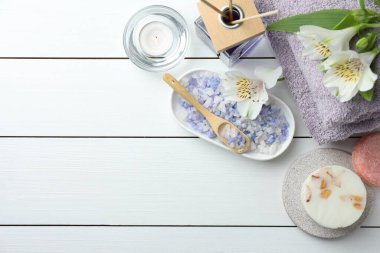 Spa kompozisyonu. Havlular, kamış oda spreyi, yanan mum, kişisel bakım ürünleri ve beyaz ahşap masada deniz tuzu, düz yatak. Metin için boşluk