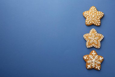 Lezzetli yıldız şekilli Noel kurabiyeleri mavi arka planda kremalı, düz yatıyordu. Metin için boşluk
