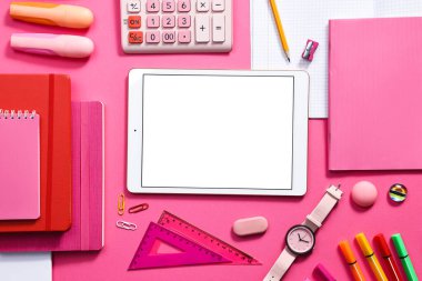 Modern tablet, hesap makinesi ve pembe arka planda kırtasiye malzemesi, düz konum. Metin için boşluk