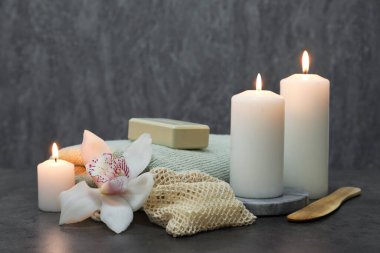 Gri masadaki farklı spa ürünleri ve orkide çiçeğiyle kompozisyon