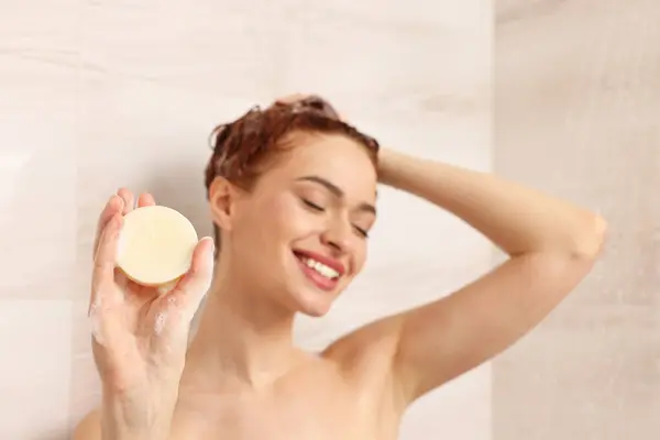 stock image Happy young woman with solid shampoo bar in shower, selective focus