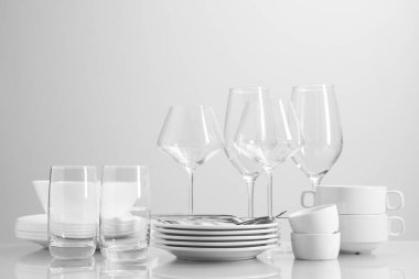 Masada bir sürü temiz bulaşık takımı, çatal bıçak takımı ve bardak var.