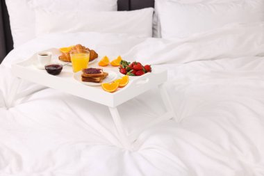 Yatakta nefis bir kahvaltı tepsisi, yakın plan. Metin için boşluk