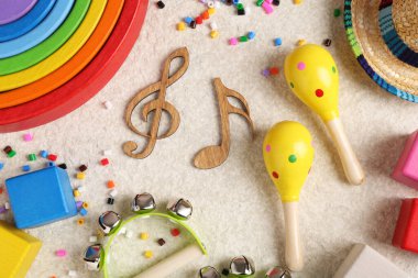 Bebek şarkısı konsepti. Tahta notalar, çocuklar müzik aletleri ve bej halıda oyuncaklar, düz uzanma