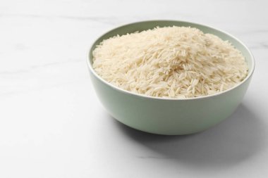 Beyaz mermer masada, kase içinde çiğ basmati pilavı, metin için yer.