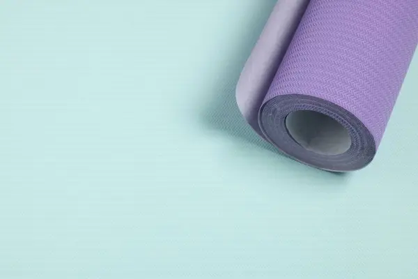 One violet wallpaper roll on light turquoise sample, above view. Space for text