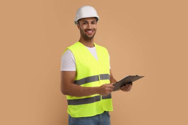 Kask takan mühendis bej arka planda pano tutuyor.