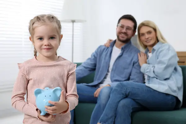 ファミリー予算 家で豚バンクと彼女の両親を持つ小さな女の子 選択的な焦点 — ストック写真