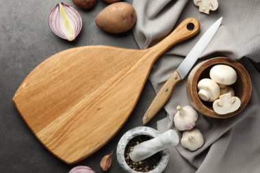 Tahta kesme tahtasıyla düz kompozisyon ve koyu dokulu masa üzerinde ürünler.