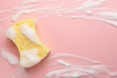 Pembe arka planda köpüklü sarı sünger, üst manzara. Metin için boşluk
