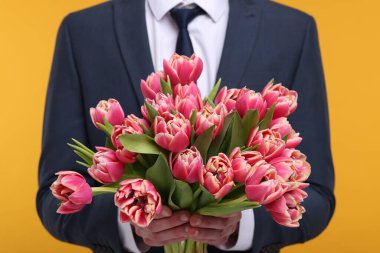 Turuncu arka planda güzel buketi olan adam, yakın plan.