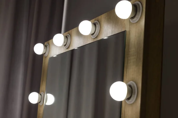 Beautiful mirror with light bulbs in makeup room, closeup