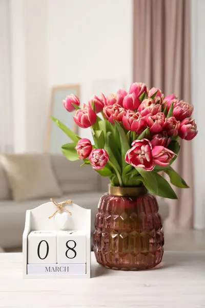 International Women\'s day - 8th of March. Block calendar and bouquet of beautiful tulips on white wooden table