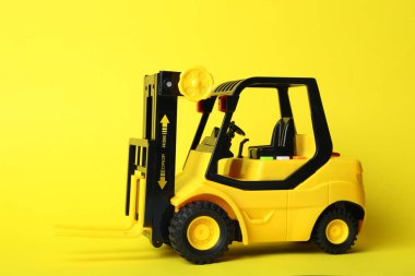 Sarı arka planda oyuncak forklift. Lojistik ve toptan satış kavramı