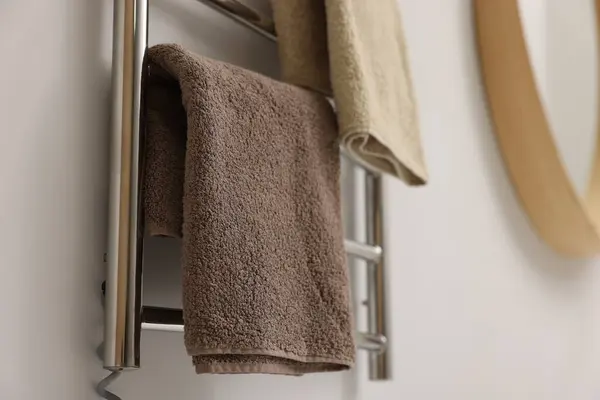 Heated towel rail with brown towels in bathroom, closeup