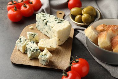 Tahta kesme tahtası ve koyu dokulu masa üzerindeki ürünler, yakın plan.