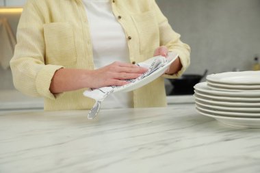 Mutfaktaki beyaz mermer masaya havluyla silen kadın, yakın plan.