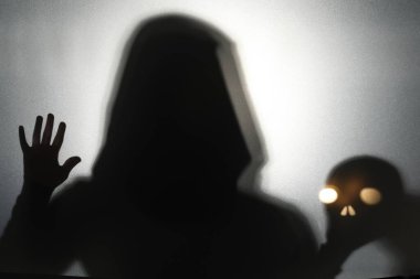 Hayalet ve kafatası silueti açık gri arka planda cam arkasında