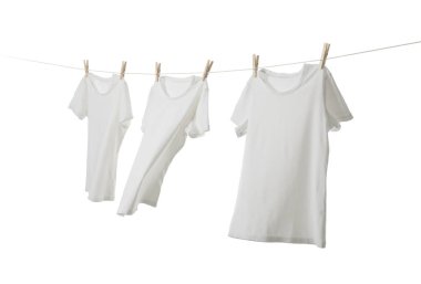 Çamaşır ipinde kuruyan birçok tişört beyaza izole edilmiş.