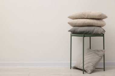 Yumuşak yastıklar ve bej duvarın yanındaki yan masa, metin için boşluk.