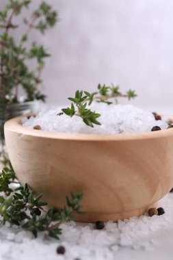 Kekikli tuz ve biberler beyaz masada kasede, yakın plan.