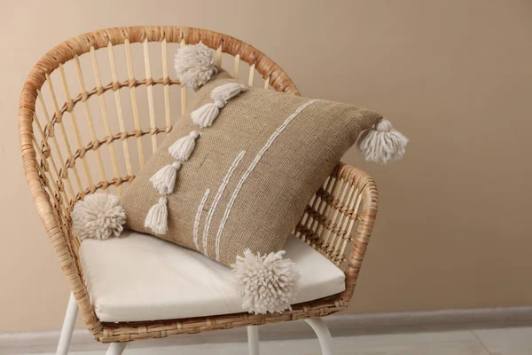 Stylish soft pillow on armchair near beige wall indoors. Space for text