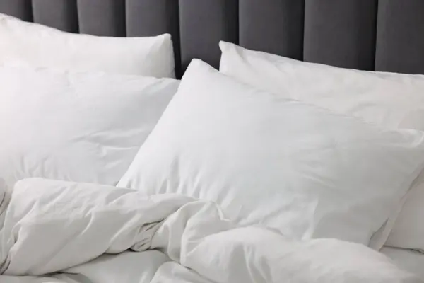 Soft white pillows and duvet on bed