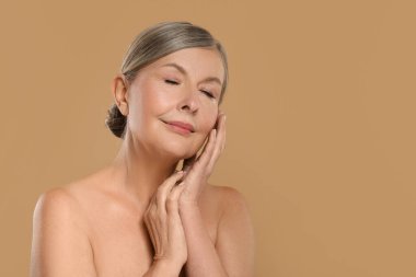 Bej arka planda sağlıklı cildi olan güzel olgun bir kadın.