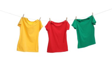 Beyaz arka planda çamaşır ipinde kuruyan farklı parlak tişörtler.