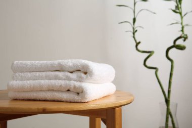 Beyaz duvara karşı tabureye katlanmış havlular, yakın plan. Metin için boşluk