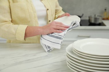 Mutfaktaki beyaz mermer masaya havluyla silen kadın, yakın plan.
