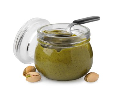 Kavanozda fıstıklı krema, beyaz tenli kaşık ve fındık.