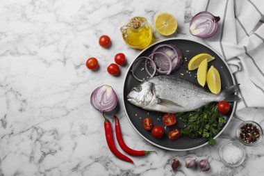 Taze dorado balığı ve malzemeler beyaz mermer masada, düz yerde. Metin için boşluk