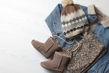 Sıcak çocuk kıyafetleri ve beyaz ahşap arka planda ayakkabılar, düz yatış. Metin için boşluk