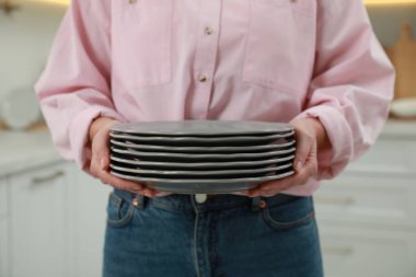 Mutfakta tabakları tutan kadın, yakın çekim manzarası.