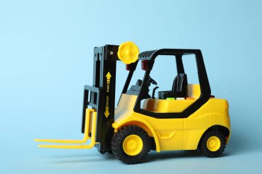Mavi arka planda oyuncak forklift. Lojistik ve toptan satış kavramı