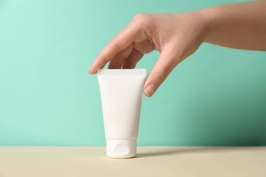 Bej masadaki el kremi tüpüyle turkuaz arka plan, yakın plan.