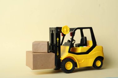 Bej arka planda kutuları olan oyuncak forklift. Lojistik ve toptan satış kavramı