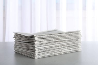 Açık gri masada yığınla gazete. Gazeteci işi.