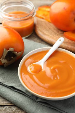 Lezzetli hurma reçeli ve ahşap masada taze meyve.