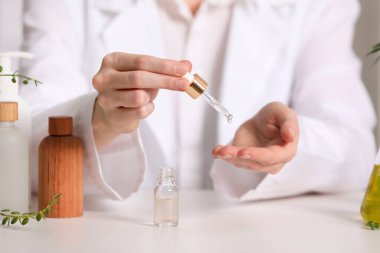 Dermatolog beyaz masada gerekli yağı test ediyor, seçici odaklanma