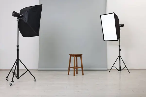 Empty stool surrounded by professional lighting equipment in photo studio